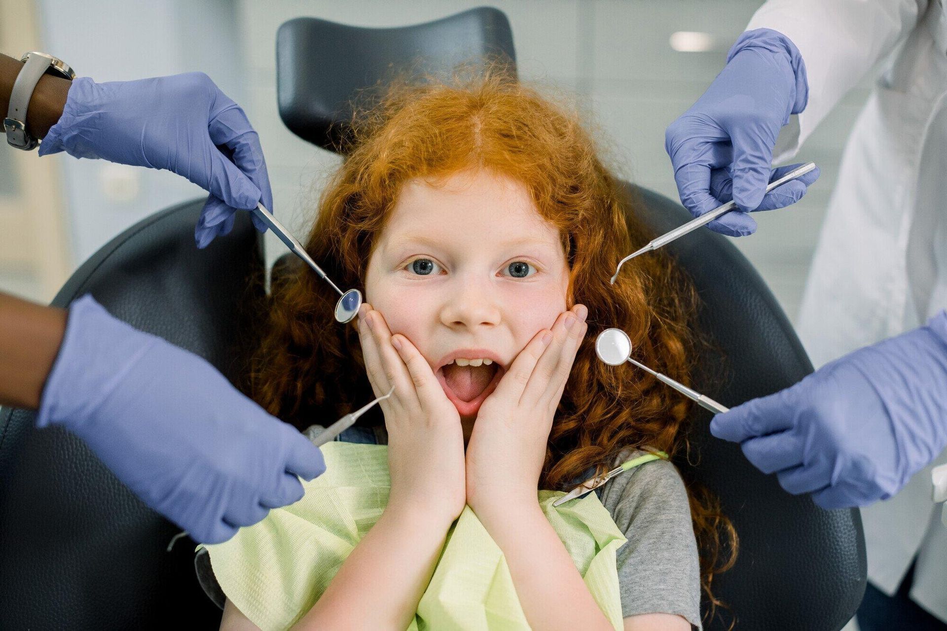 A little girl is sitting in a dental chair being examined by a dentist.