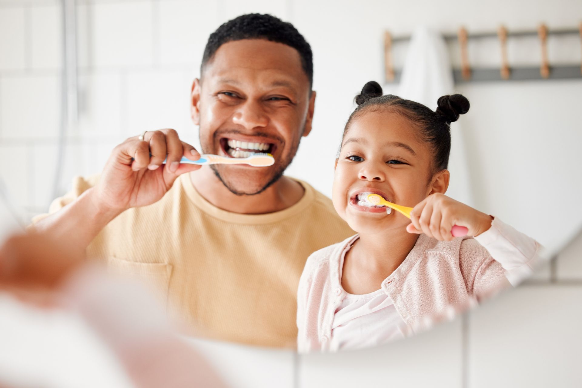 Man and child brushing teeth together in bathroom.
