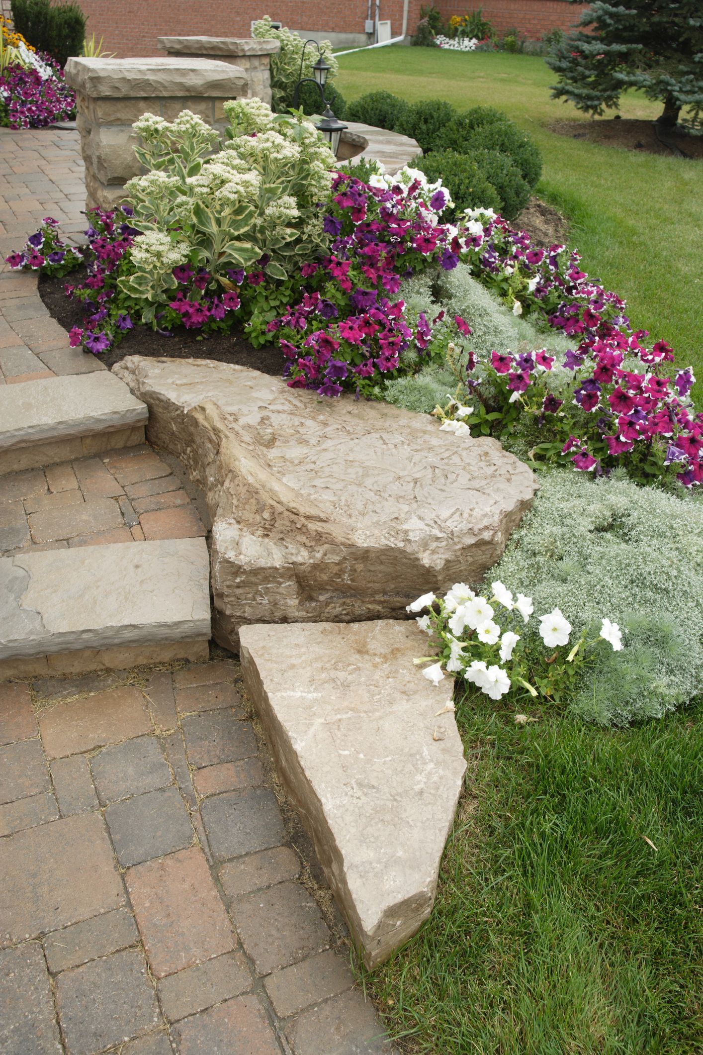 A stone walkway with steps leading up to a garden filled with flowers.