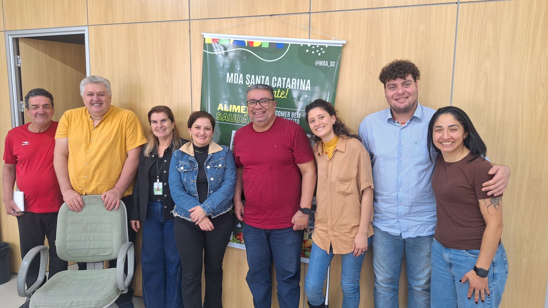 Mulher colhendo tomates e pimentões em uma horta, agachada ao lado das plantas frondosas.
