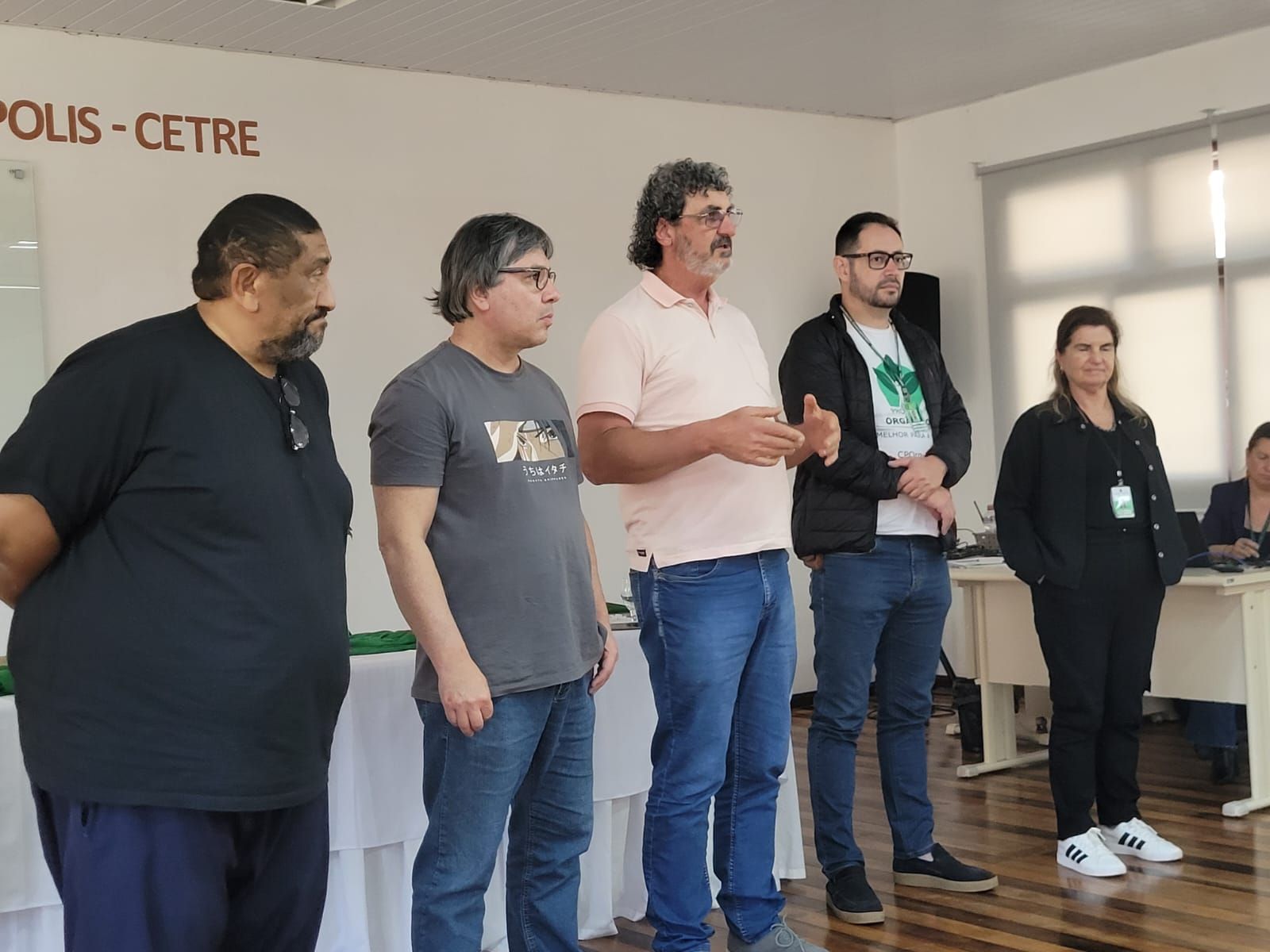 Mulher colhendo tomates e pimentões em uma horta, agachada ao lado das plantas frondosas.