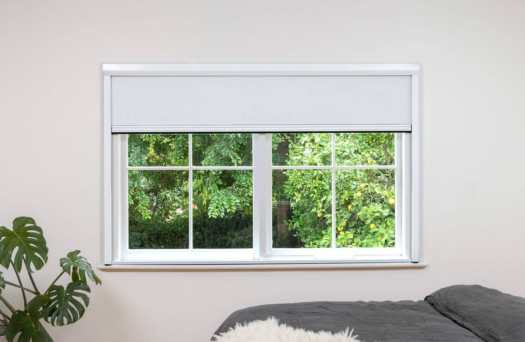 White frame and white fabric full blackout blinds installed on a wide window, outside installation.
