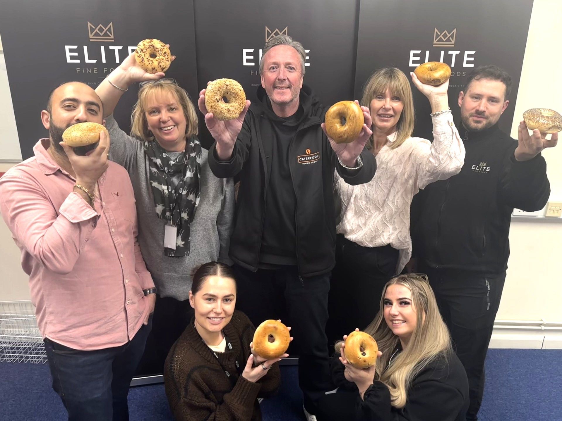 Team of seven people holding up bagels to celebrate the launch of this new brand in the UK