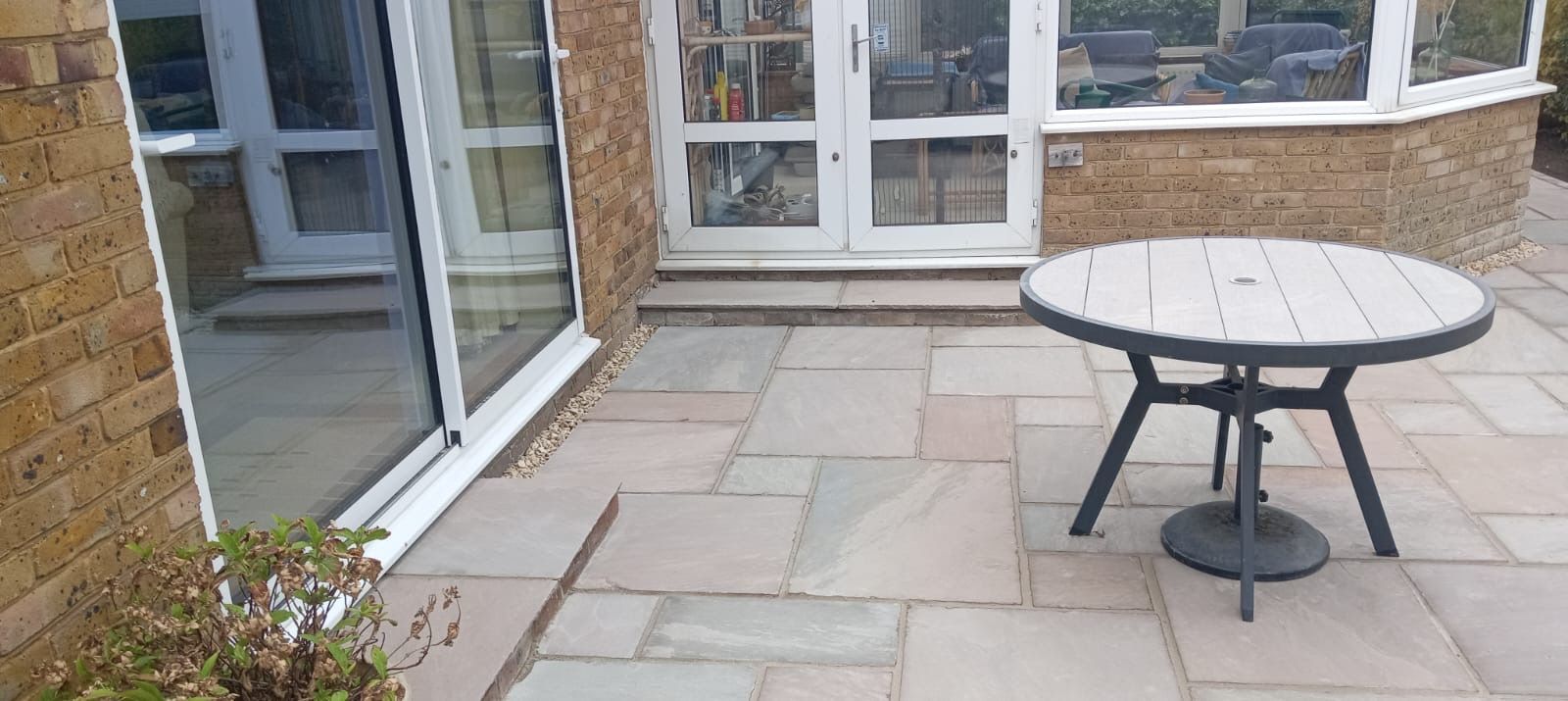 Patio with stone paving, glass doors, and a round outdoor table