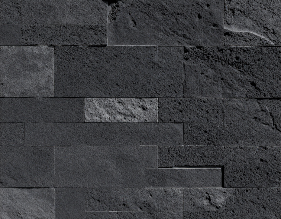 Parete in pietra grigio scuro con blocchi rettangolari sfalsati e una texture ruvida