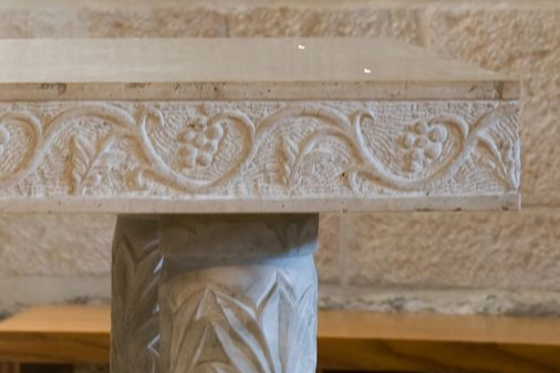 Caminetto in pietra scolpita o in gesso, con elaborati motivi floreali a volute, su una parete beige