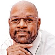 A bald man with a beard wearing glasses and a white shirt.