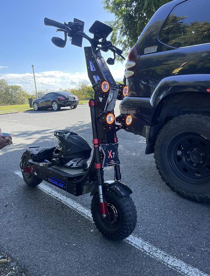 A Scooter is Parked in a Parking Lot Next to a Car — EVA Motors in Paget, QLD