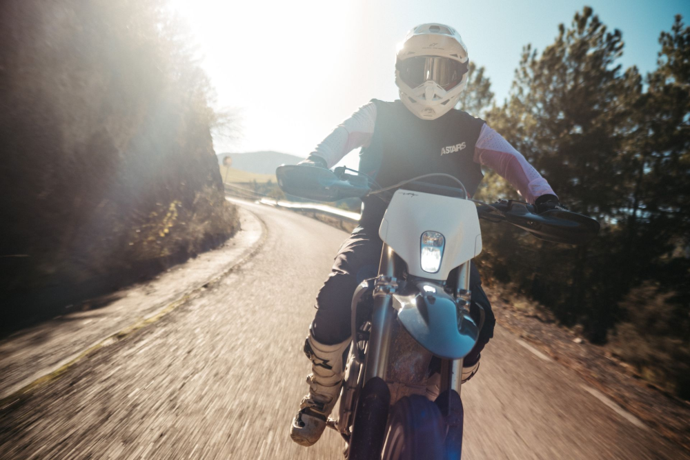 Motorcyclist riding on a road; wearing helmet and protective gear, backlit by sun. — EVA Motors in Paget, QLD