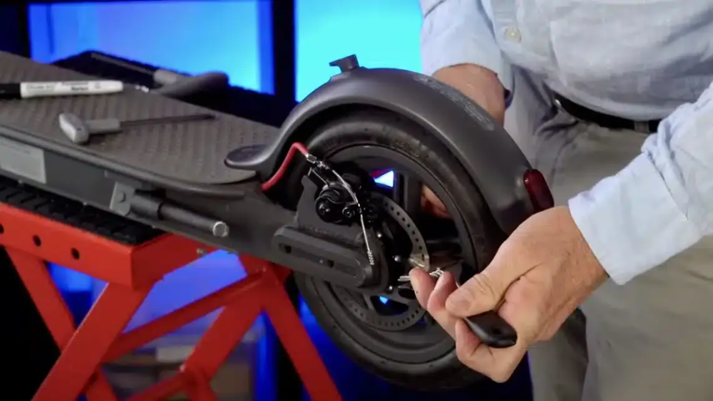Person repairing an electric scooter's rear wheel, using a tool— EVA Motors in Paget, QLD