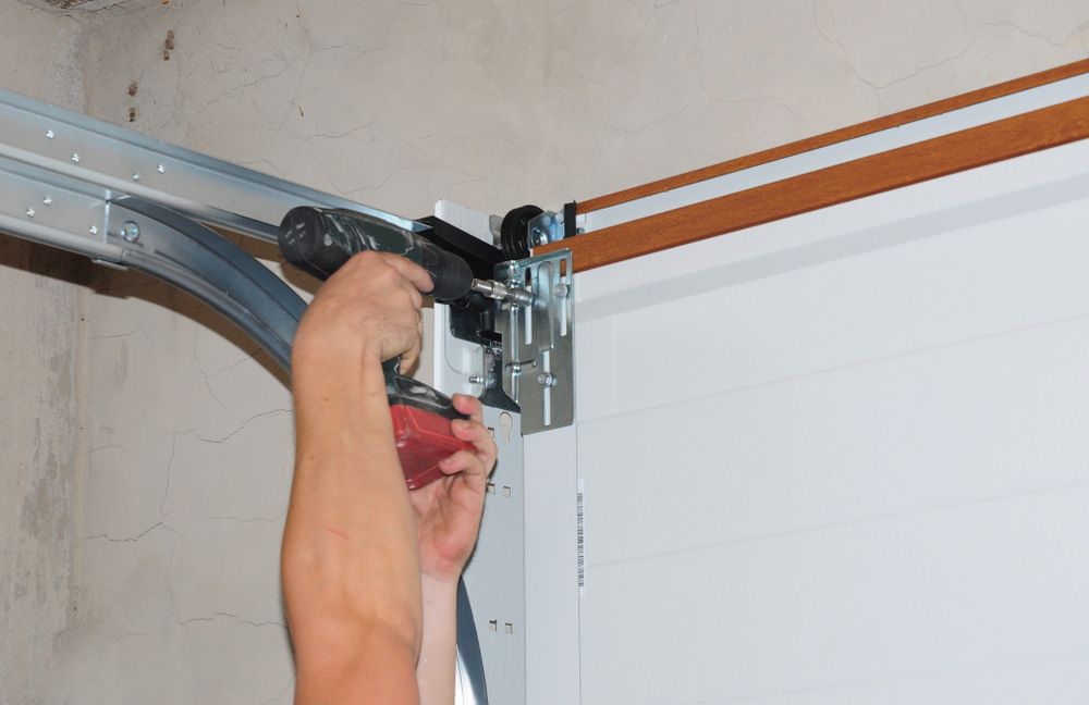A Person is Fixing a Garage Door With a Screwdriver — Hastings Garage Door Services in Port Macquarie