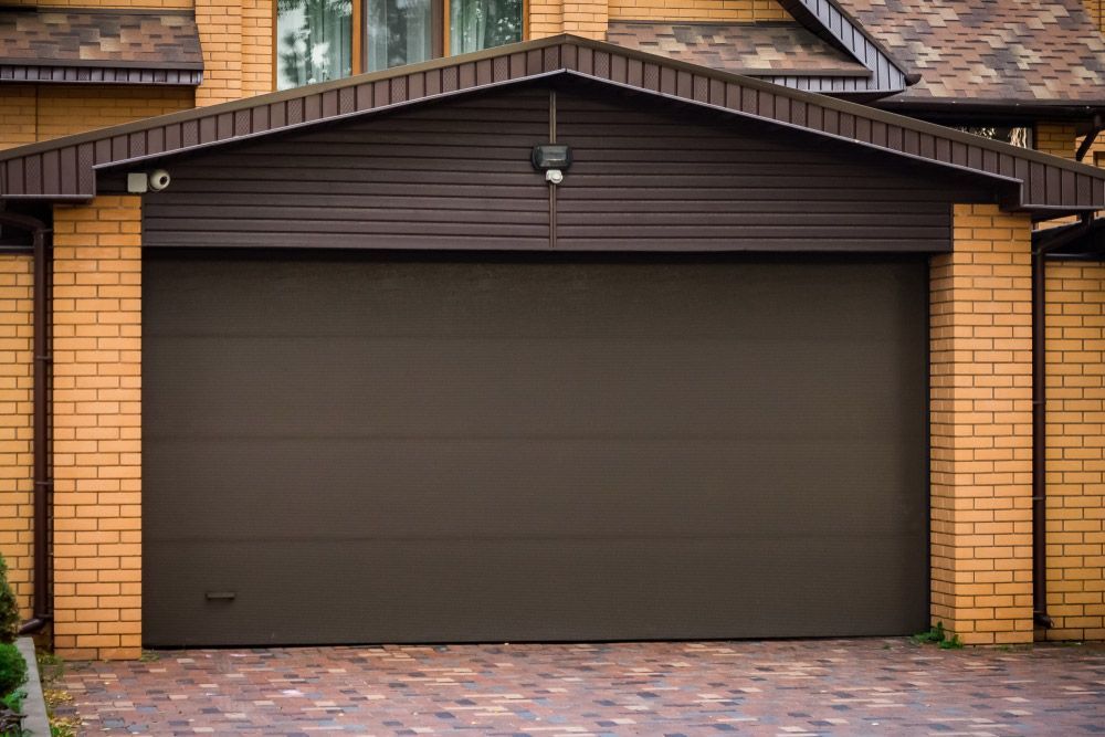 A Brown Garage Door is Sitting in Front of a Brick House — Hastings Garage Door Services in Port Macquarie
