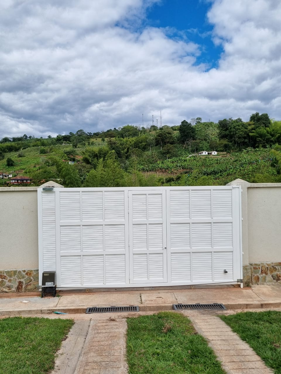 Un tirador de puerta moderno, fabricado en metal cepillado y cristal transparente, fijado a una puerta metálica.