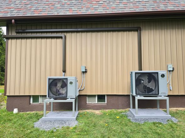 Basement wall with three electrical breaker panels and exposed wiring on concrete walls