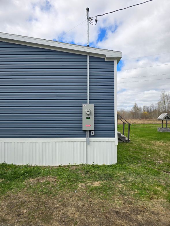 Gray electrical meter box mounted on a wall with conduit and outlet below