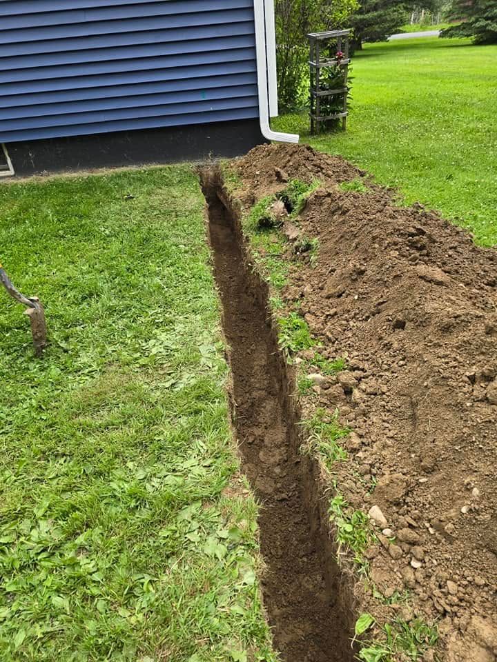 Long narrow trench dug beside a house on a grassy lawn