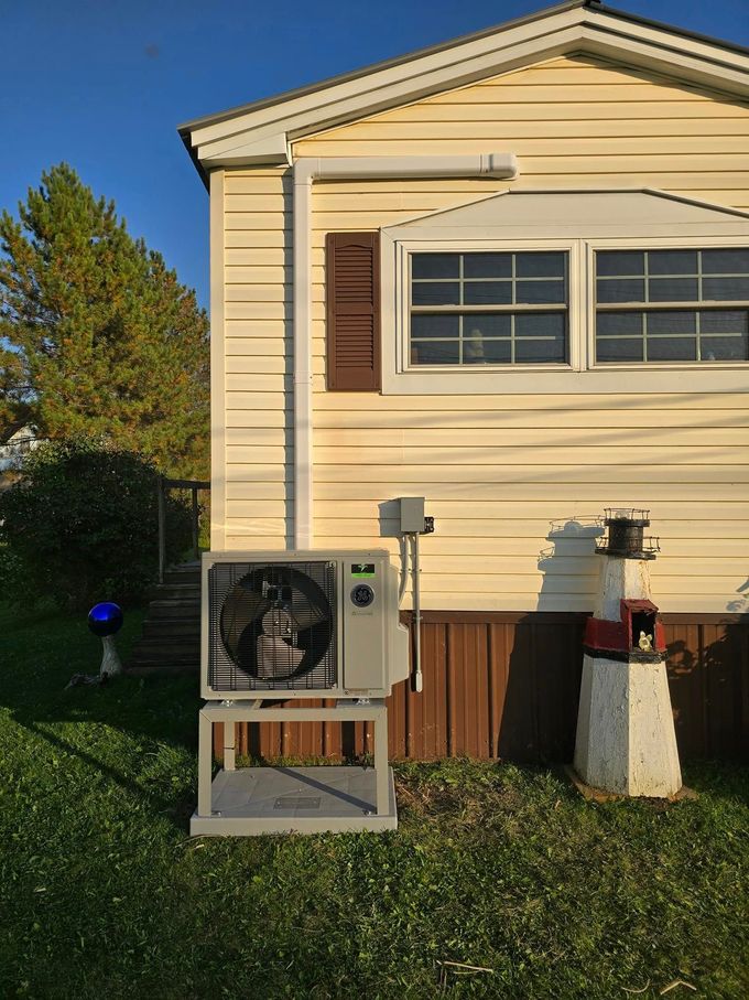 House exterior with two outdoor HVAC units beside beige siding and a window at sunset