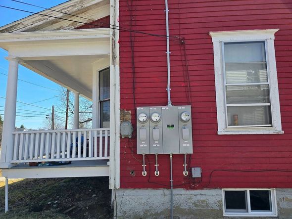 Red house exterior with utility meters and a white porch on the side.