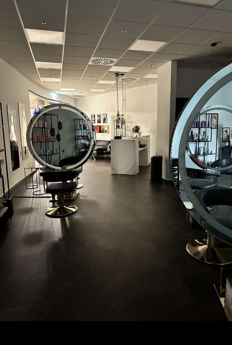 Ein Friseursalon mit einem großen runden Spiegel in der Mitte des Raumes.