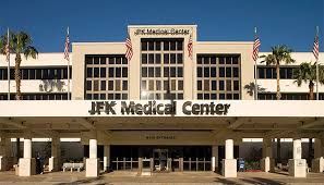 Front entrance of JFK Medical Center with beige facade and American flags