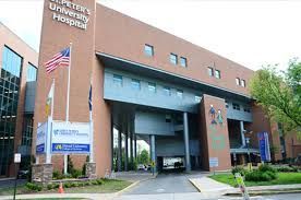 Modern brick hospital entrance with flags and a covered driveway
