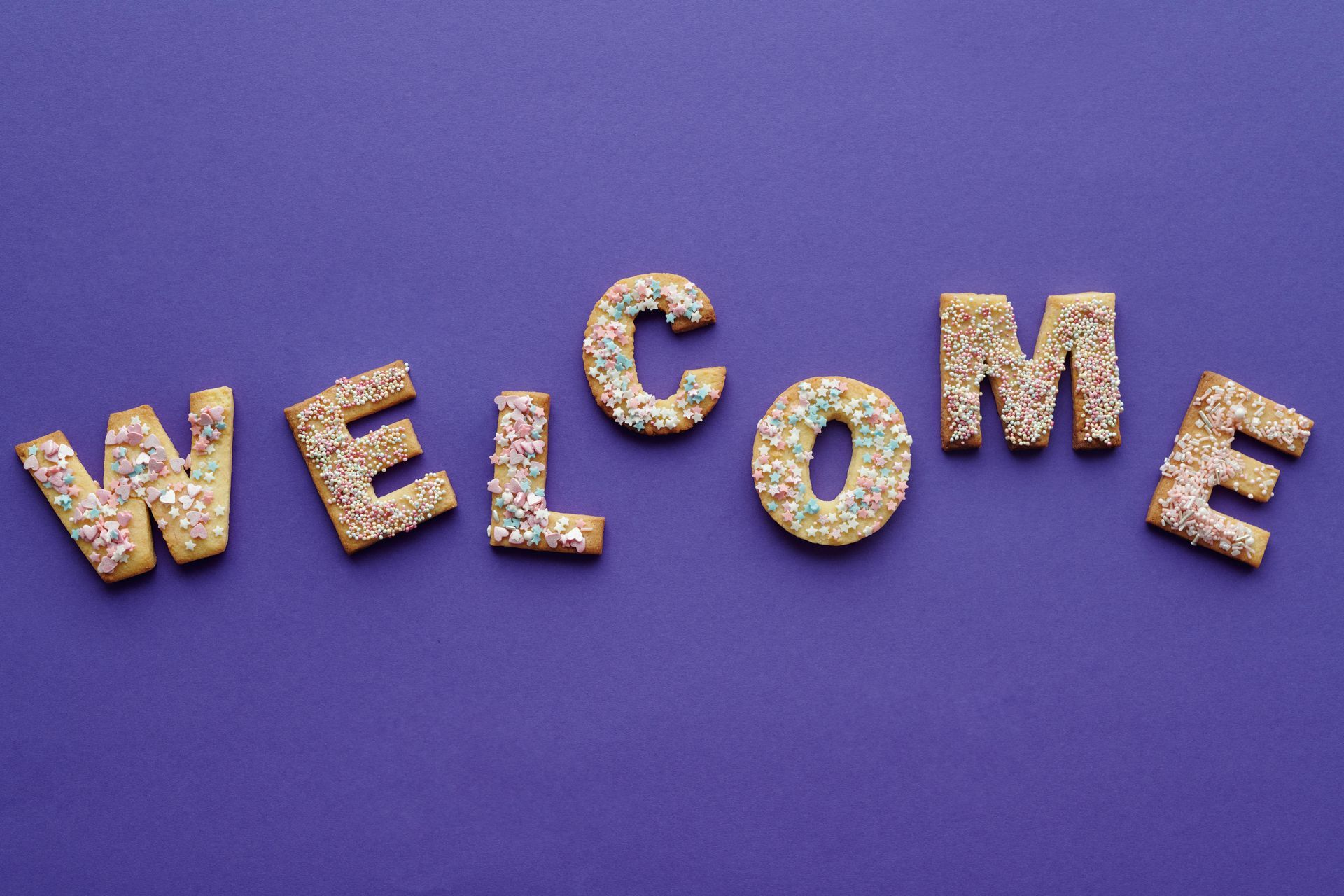 “WELCOME” spelled in glittery letters on a purple background