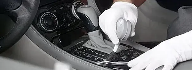 A person is cleaning the dashboard of a car with a brush.
