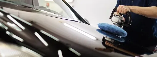 A man is polishing a car with a microfiber cloth.