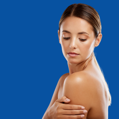 Woman with brown hair touching her shoulder, looking down. Blue background.