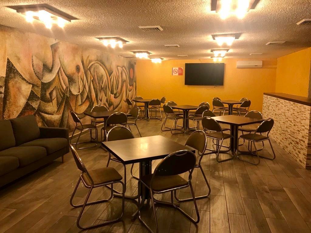 Una sala grande con mesas y sillas en el HOTEL DE CUAUTLA