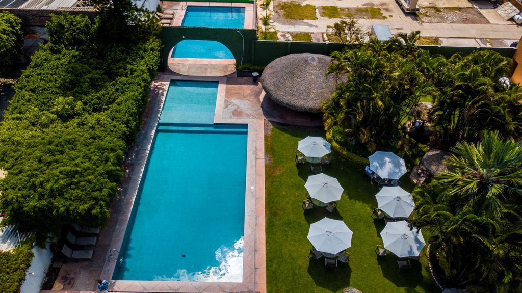 Una vista aérea de una gran piscina rodeada de mesas y sombrillas.