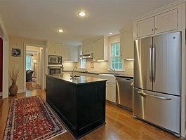 Kitchen with a black island, stainless steel appliances, and wood floors.