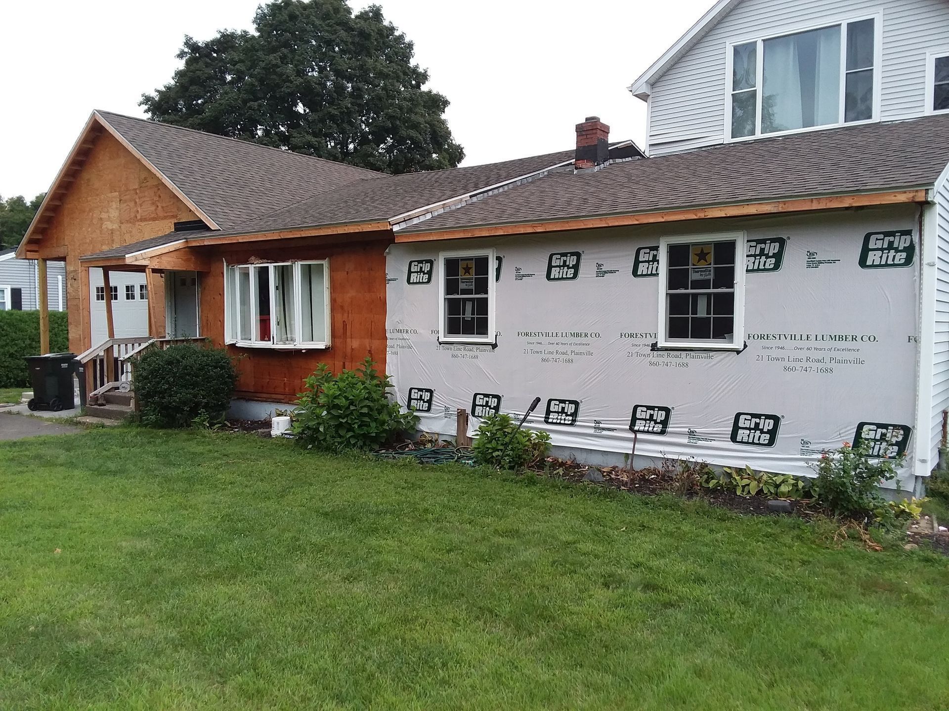 House under construction with exposed wood siding and new windows.