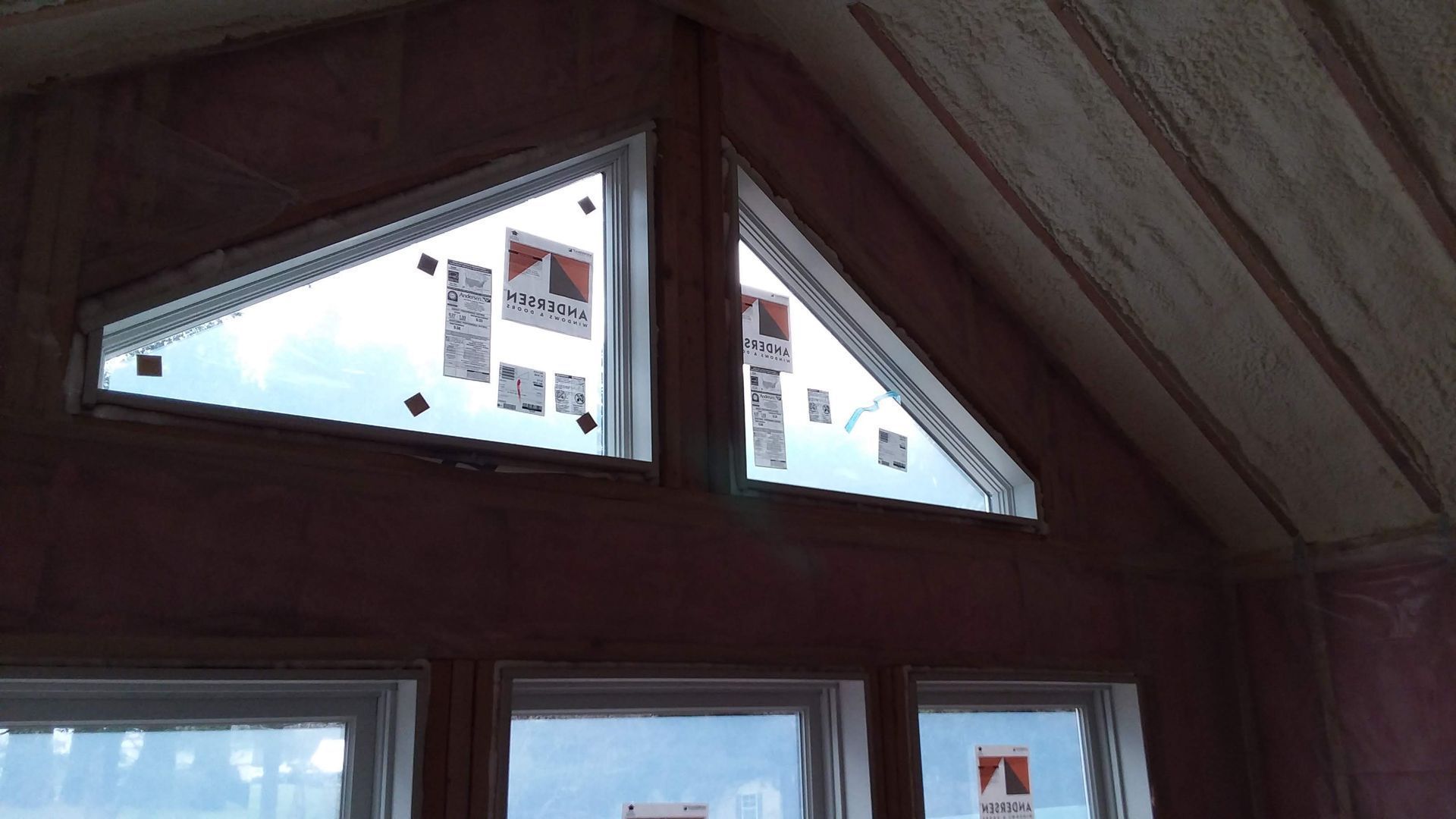 Interior view of a building under construction, featuring triangular and rectangular windows.