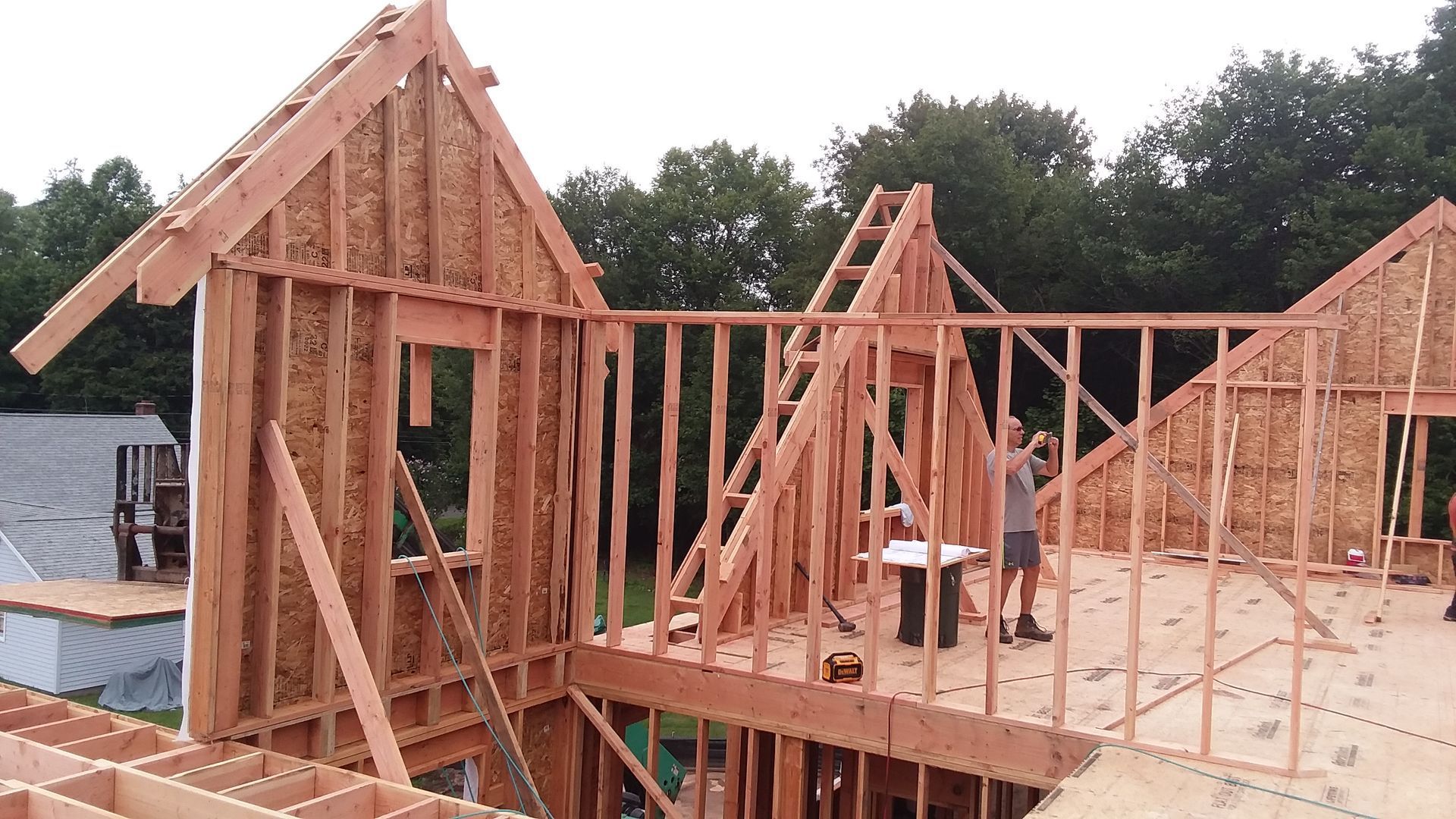 Construction of a wood-framed house in progress; a person works on the structure.