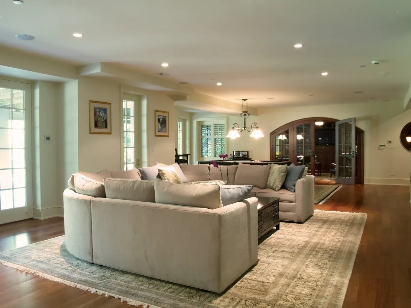 Beige sectional sofa in a bright, spacious living room with hardwood floors and an area rug.