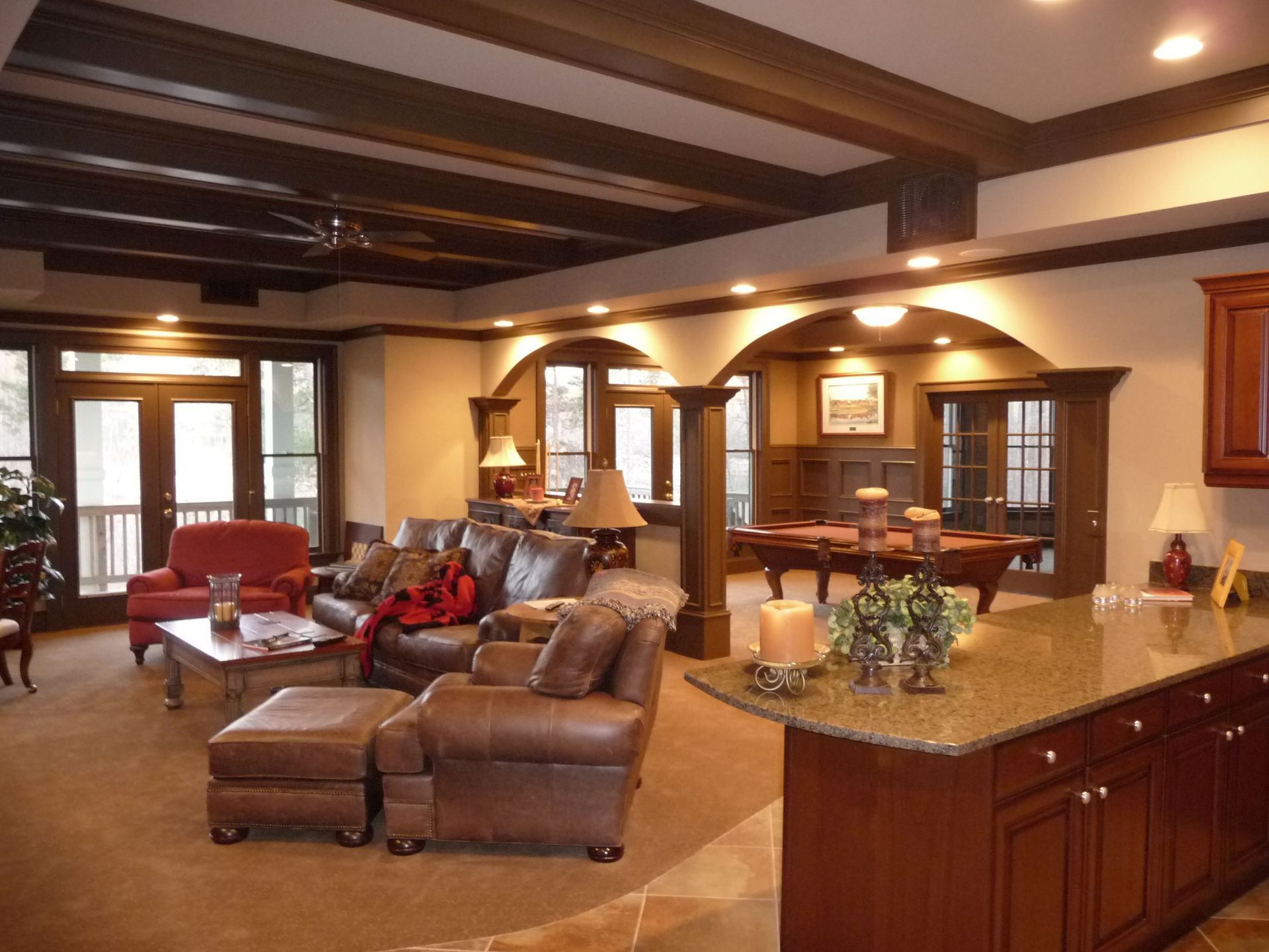 Spacious finished basement with seating areas, kitchen, and pool table. Brown and beige tones dominate.