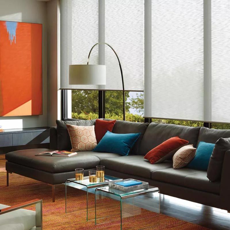 Modern living room with dark sectional sofa, glass coffee table, floor lamp, and abstract wall art