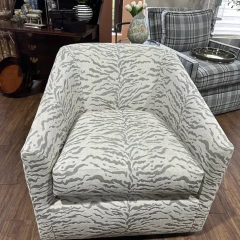 Light gray patterned armchair with a cushioned seat in a living room on a wood floor