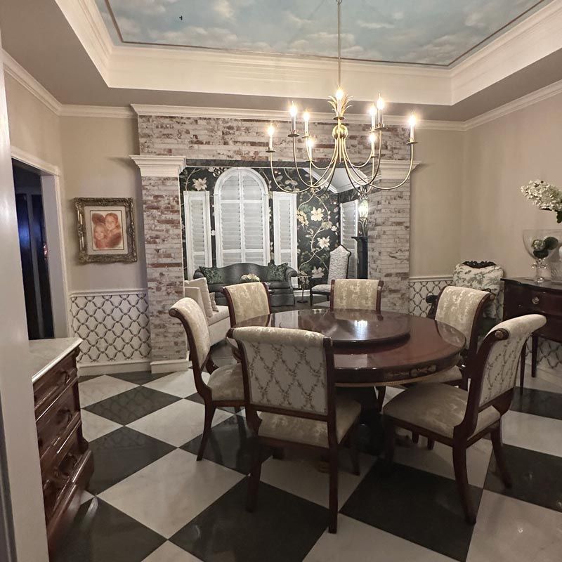 Elegant dining room with round table, upholstered chairs, chandelier, and black-and-white tiled floor