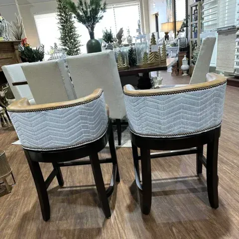 Two white upholstered chairs with black legs in a bright furniture showroom