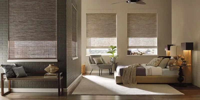 Modern living room with round glass coffee table, vase of flowers, bowl, and sunlight through blinds
