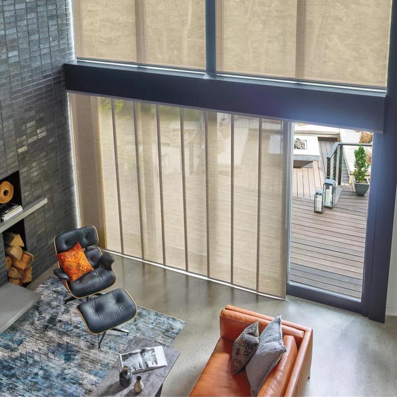 Modern living room with large windows, sectional sofa, chairs, and a view of an outdoor deck