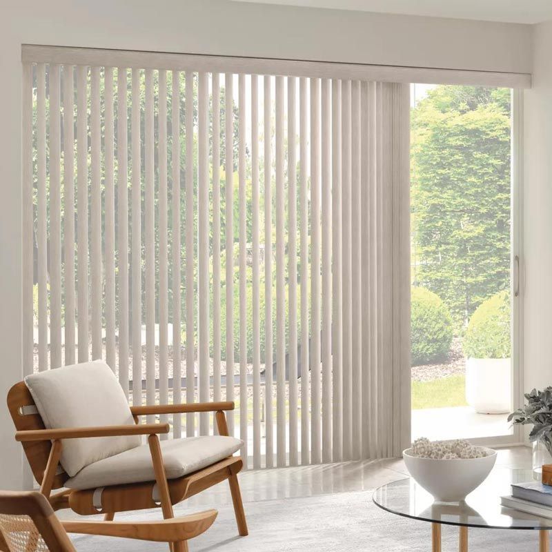 Bright living room with vertical blinds, a wooden lounge chair, and a small round coffee table.