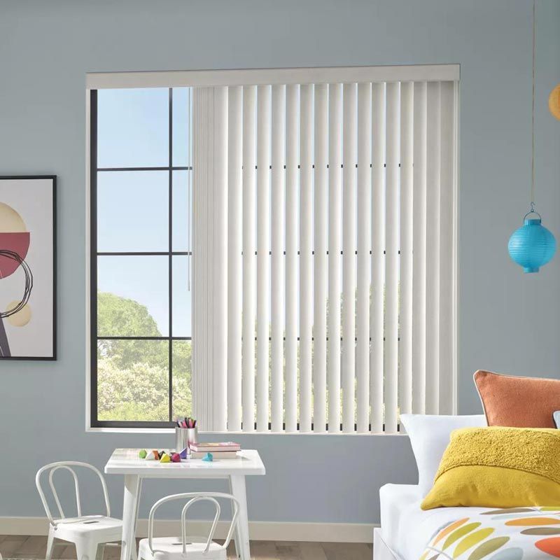 Bright living room with vertical blinds, a large window, small table, and colorful cushions on a sofa