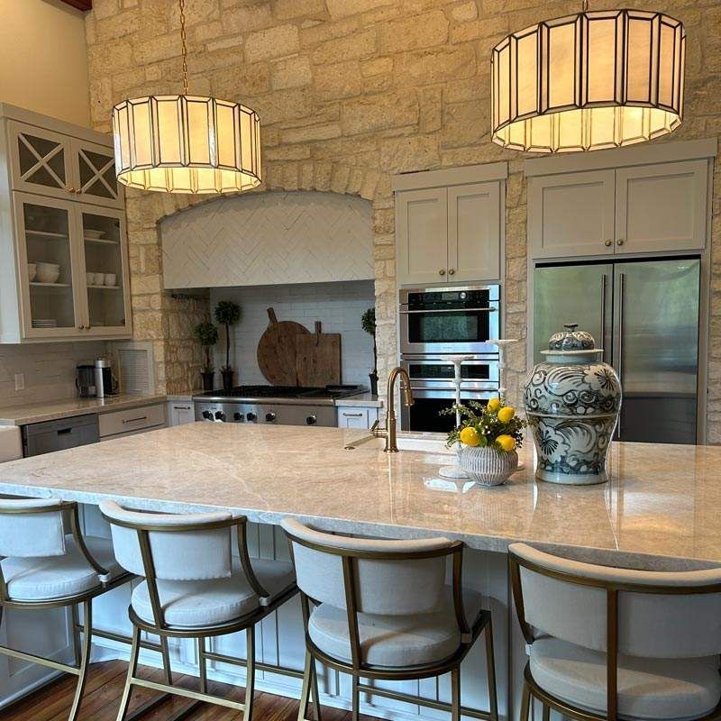 Elegant kitchen with stone walls, large island, pendant lights, and stainless-steel appliances