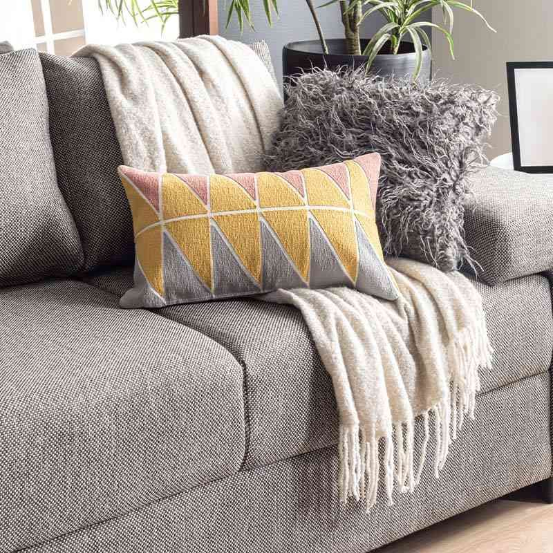 Gray sofa with a cream throw and patterned mustard pillow in a cozy living room