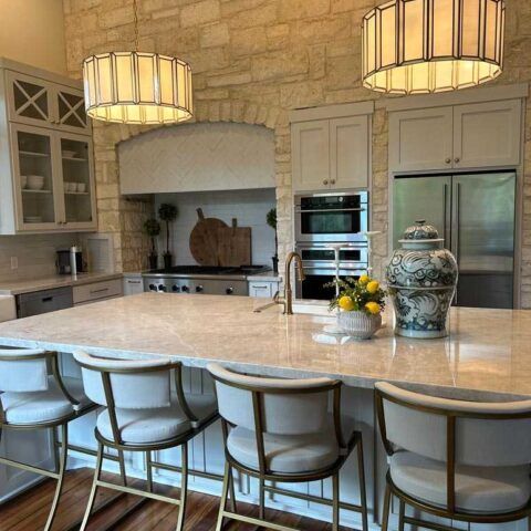 Modern kitchen with stone walls, large island, pendant lights, and stainless steel appliances