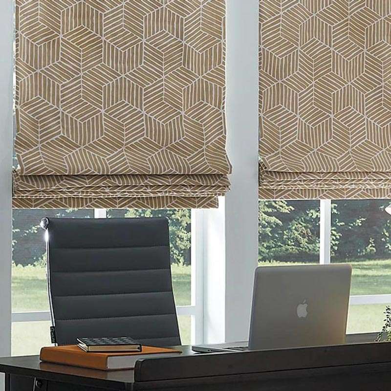 Office desk by window with closed patterned blinds, a black chair, and a silver laptop on the desk