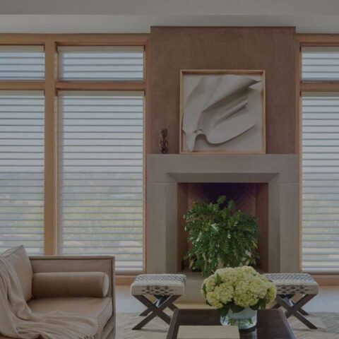 Modern living room with beige sofa, fireplace, potted plant, and large windows with blinds